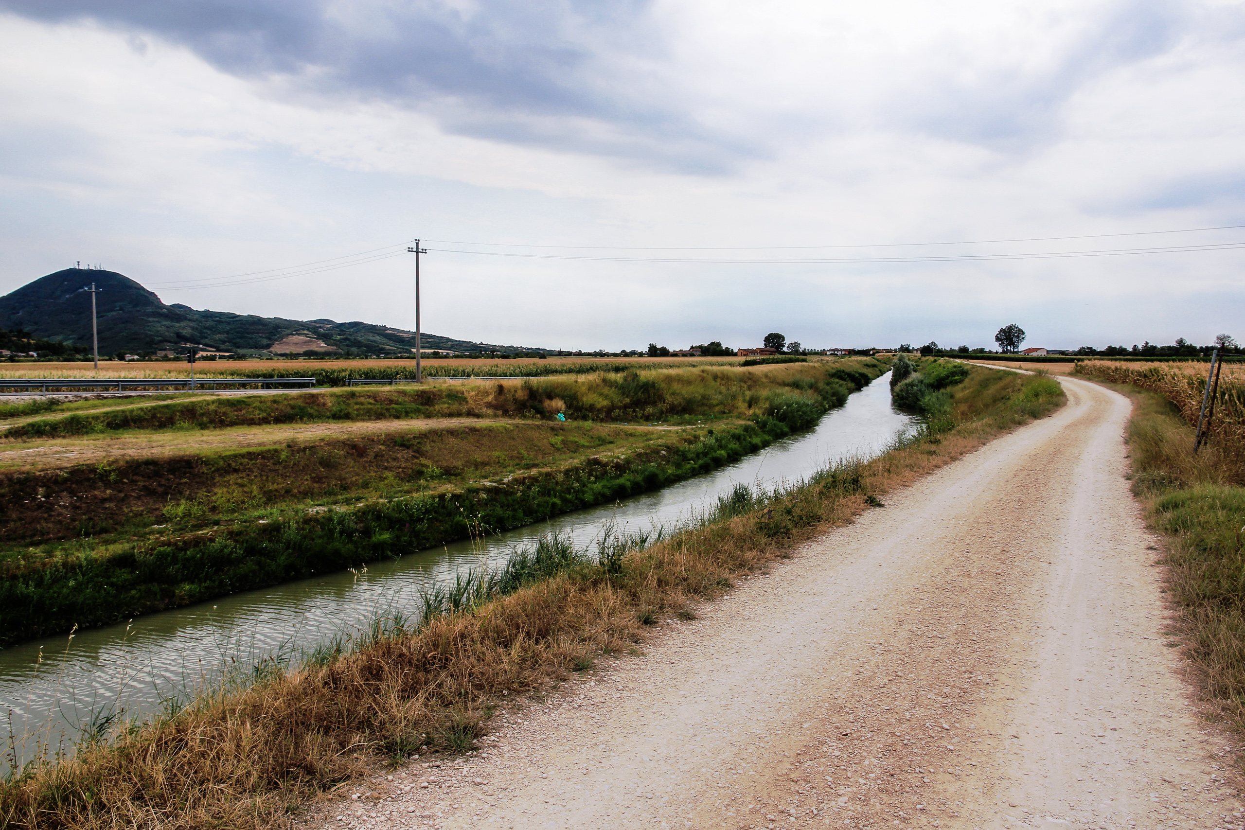 Schotterweg am Bewässerungskanal, links der Kegel eines Euganeischen Hügels